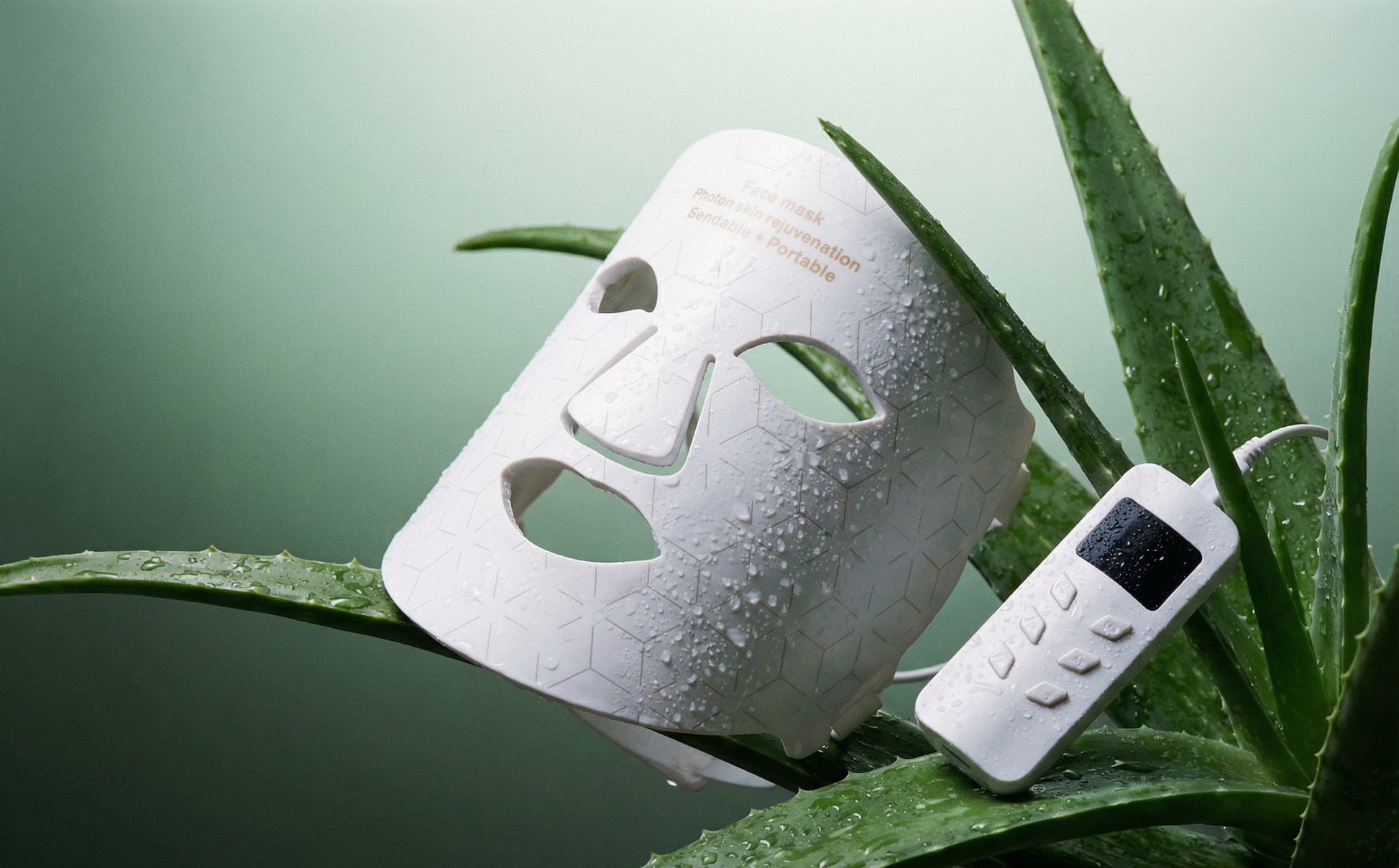 White facial mask with remote control on green leaves