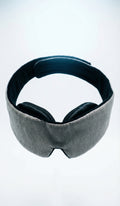 Gray sleep mask with black ear covers on a white background