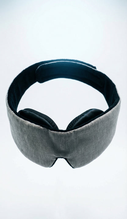 Gray sleep mask with black ear covers on a white background